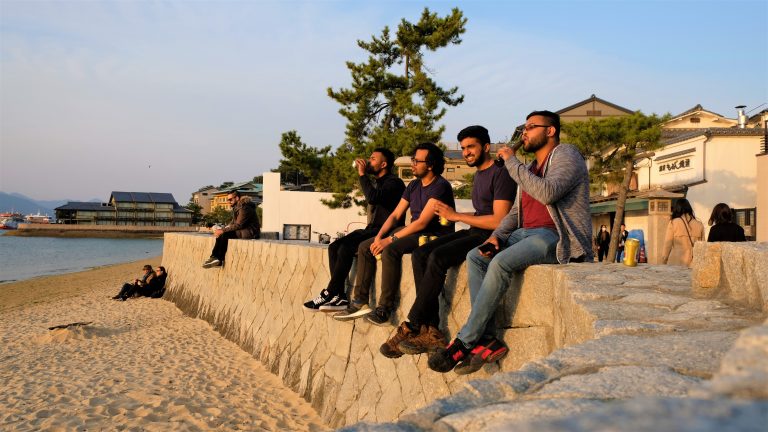 Four friends drinking a beer on the Miyajima Beach