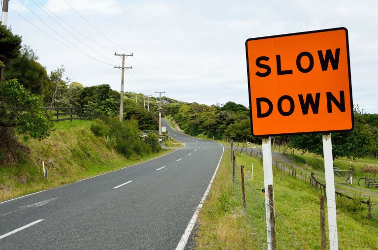 Orange Slow Down sign by a road