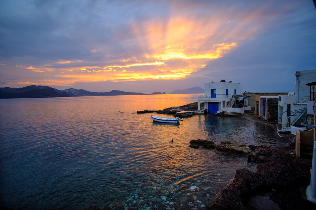 Sun shines through the clouds with view of house and boat