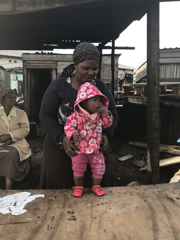 A child and her Mother stand in their poorly maintained Goat Head Meat store