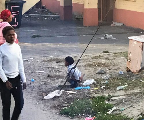 Child using bathroom near a pile of trash